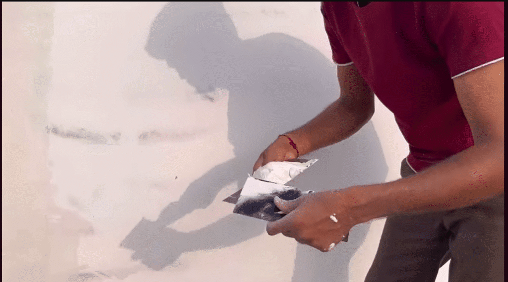 Painter adding a dark accent color to one wall in a living room.