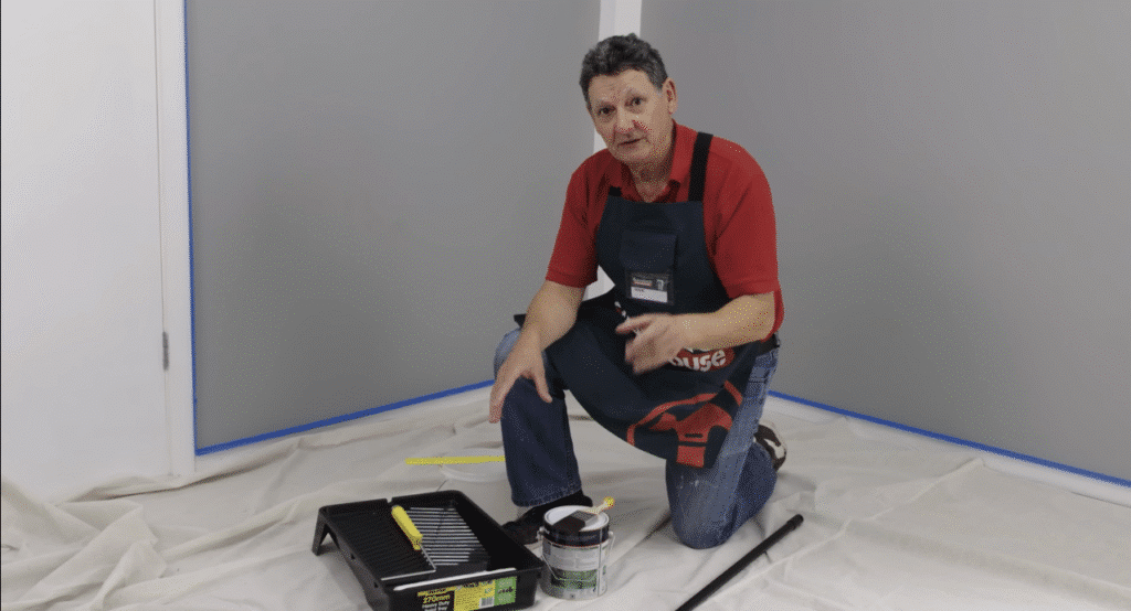Worker painting a ceiling with a roller extension.