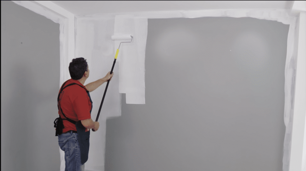 Painter touching up kitchen wall corners with white paint
