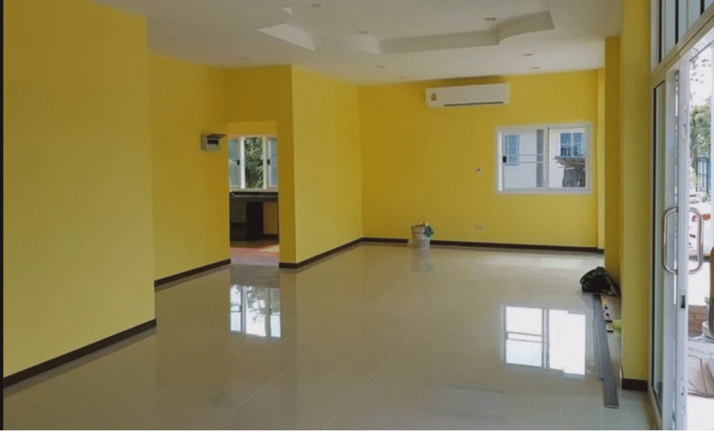 Painter completing yellow wall in a family living room.